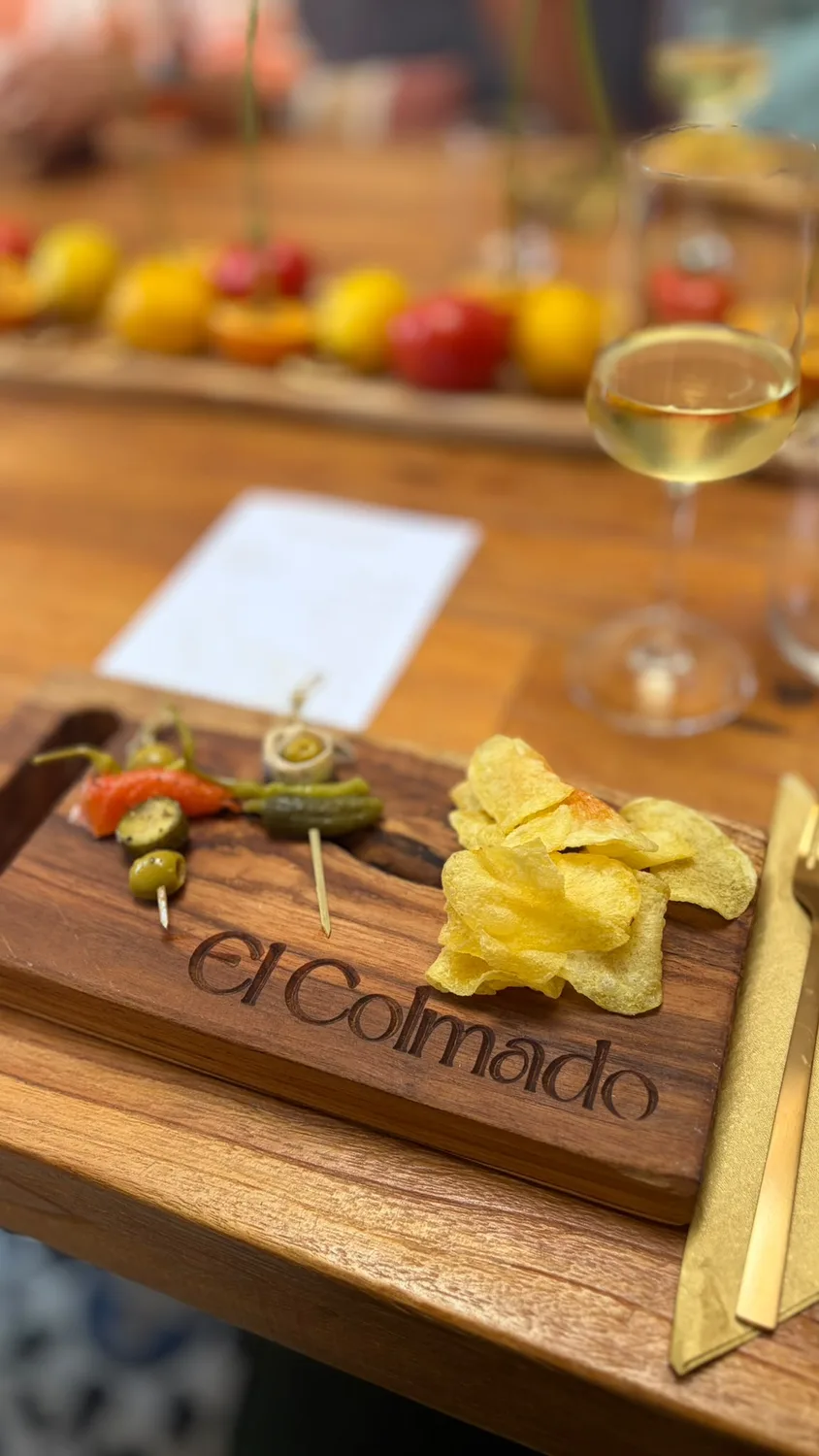 An El Colmado board with olives, crisps and wine